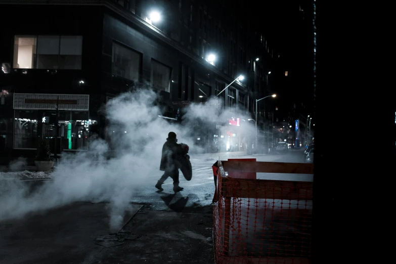 a person walks down the street as smoke comes from the sidewalk