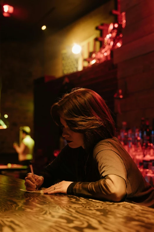 a woman sitting at a bar writing on her cellphone