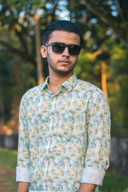 a man standing outside wearing sunglasses and a flowered shirt