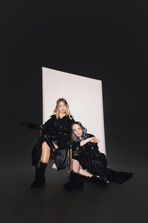 two woman sitting on a chair in the dark