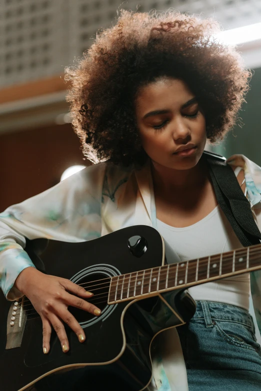 a woman playing a black acoustic guitar