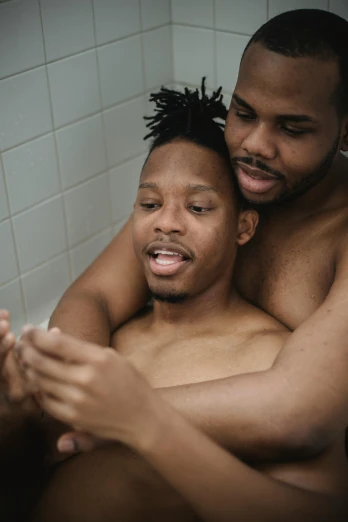 a man and child sitting in the tub taking a shower together