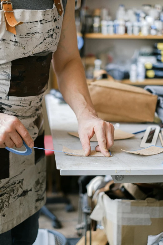 someone wearing an apron is making pieces of wood