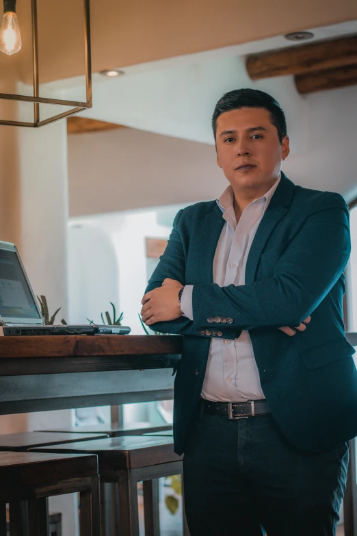 a man standing next to a table with a laptop on it