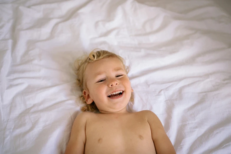 a baby with  on laying in a bed smiling