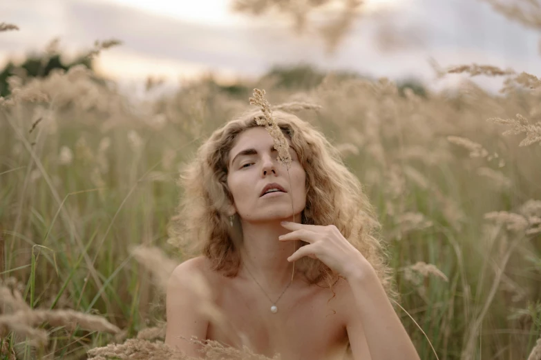 woman sitting in long grass smoking a cigarette