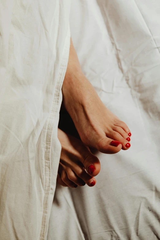 a woman with red and white nails standing on a bed