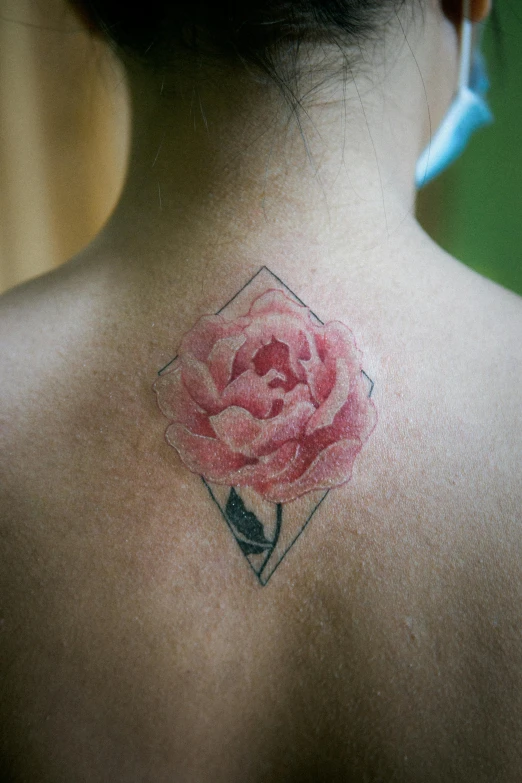 a woman's back tattoo with a flower on her shoulder