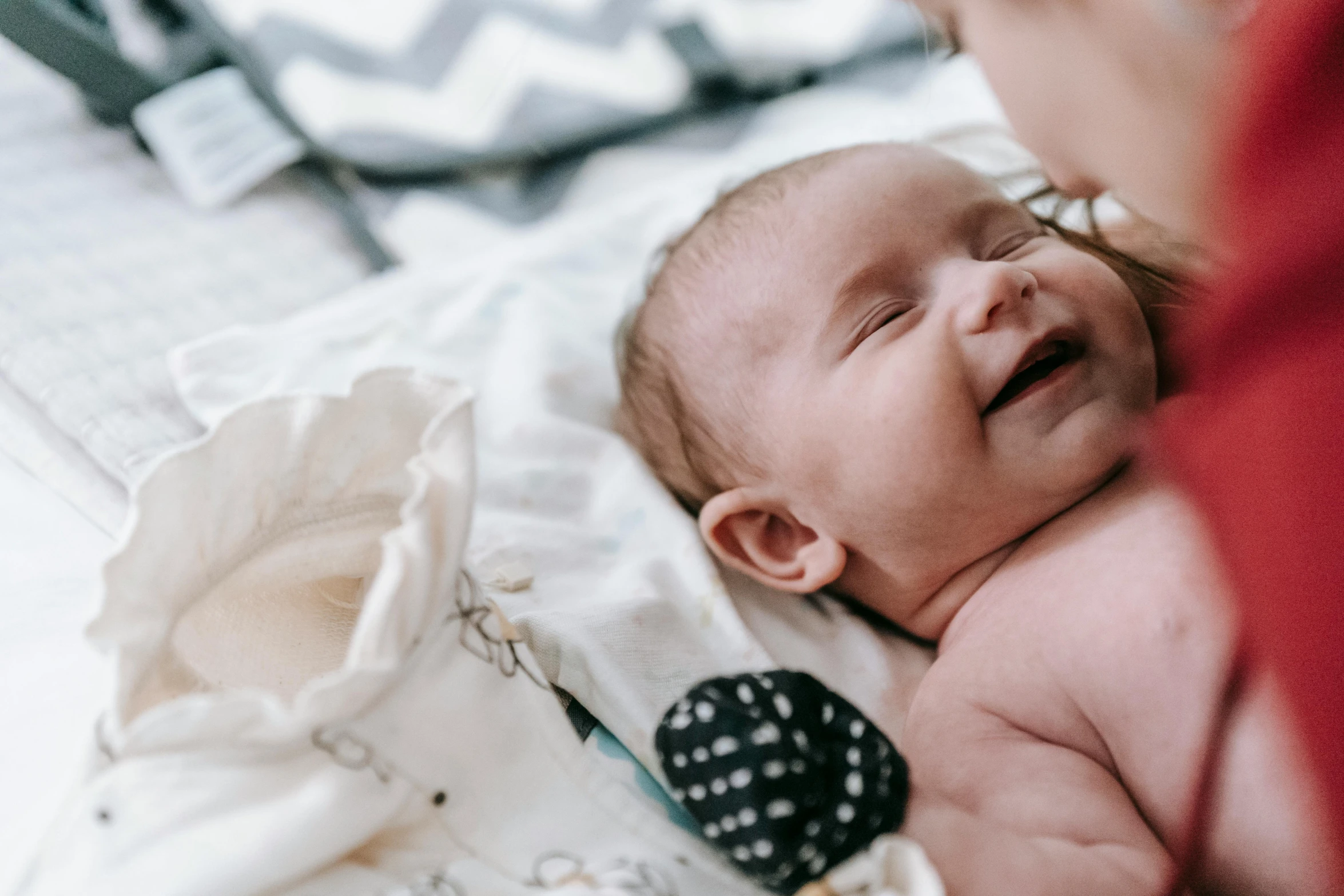 a small baby sleeping on its side next to someone