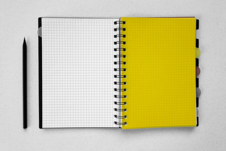 a yellow notebook with black and white squares is next to a black pen on top of it