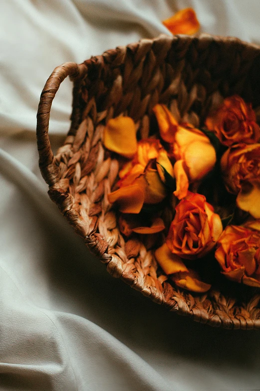 dried roses in an empty basket on a bed