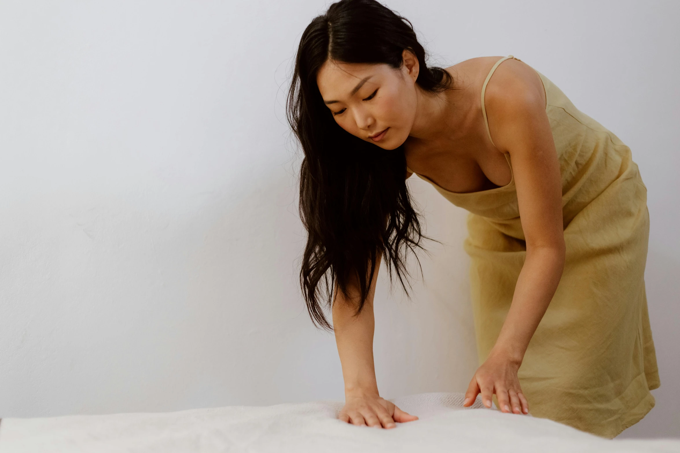 a woman bends over with her hands on a pillow