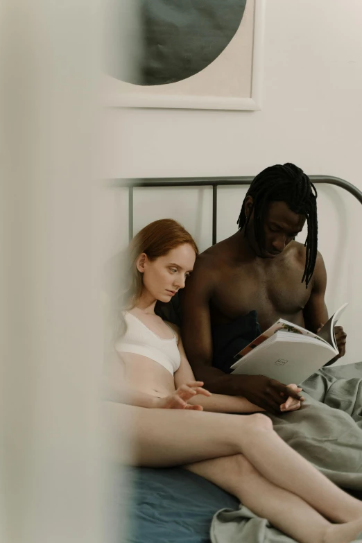 a woman reading a book to a man in bed