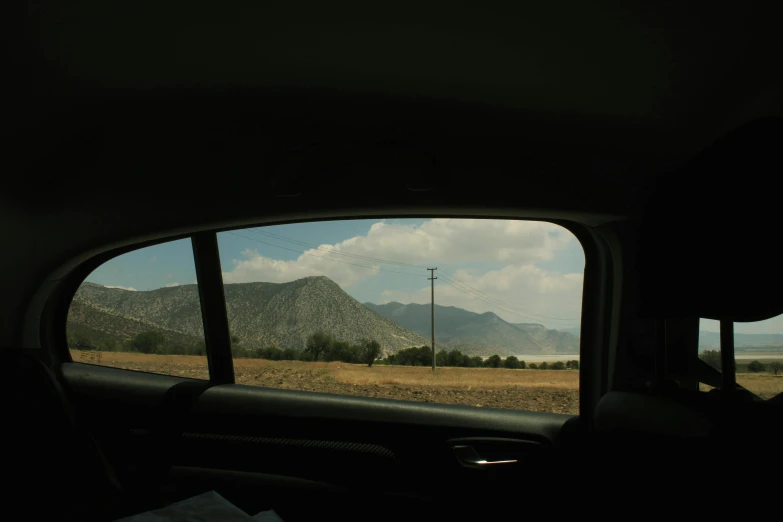 a side view mirror reflecting a field and mountains