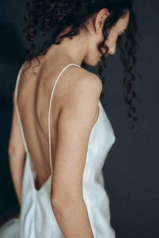 a woman in a white dress looks down at the side of her dress