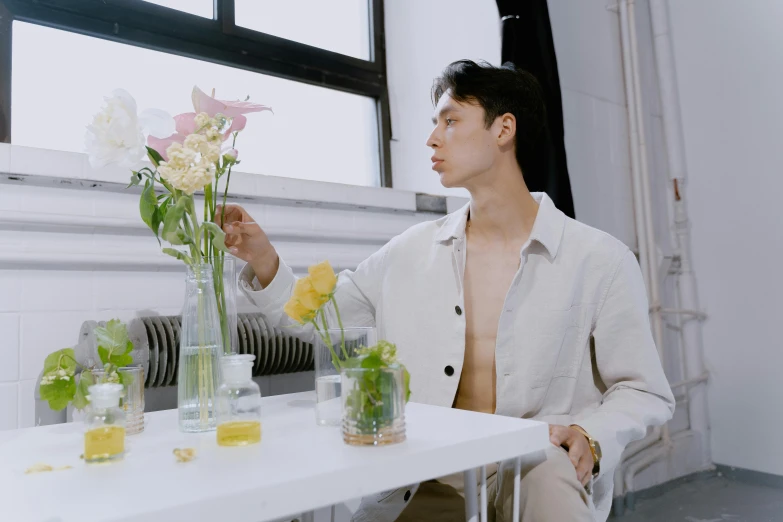 a man sitting in front of a table with flowers in vases