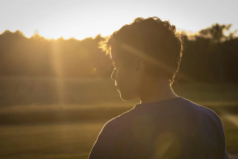 the man is standing in front of the bright sun