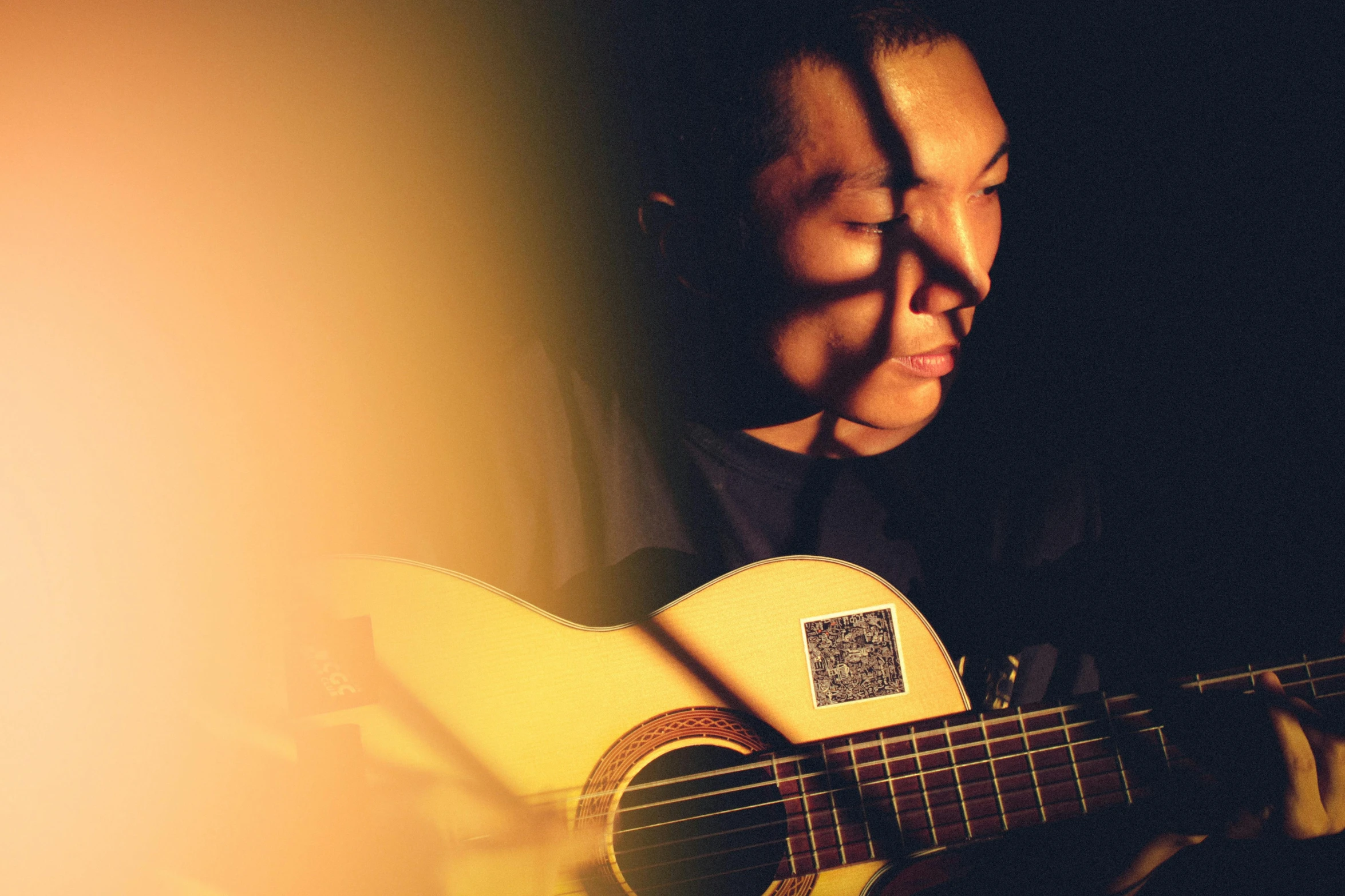 a person holding a guitar with their face illuminated in the background