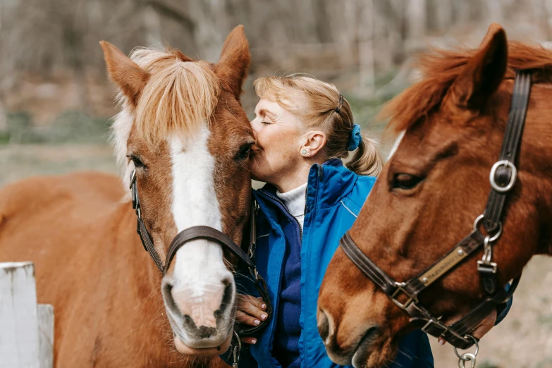 a woman kissing her horse outside in a field