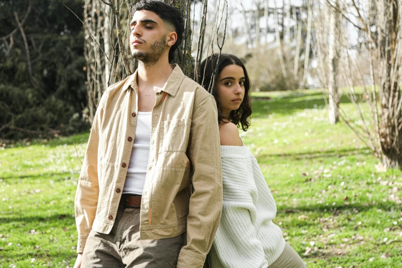 a man and woman walking down a tree lined field