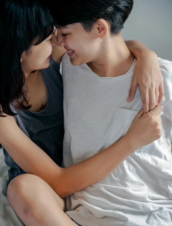 an asian man and a woman, both are emcing on the bed