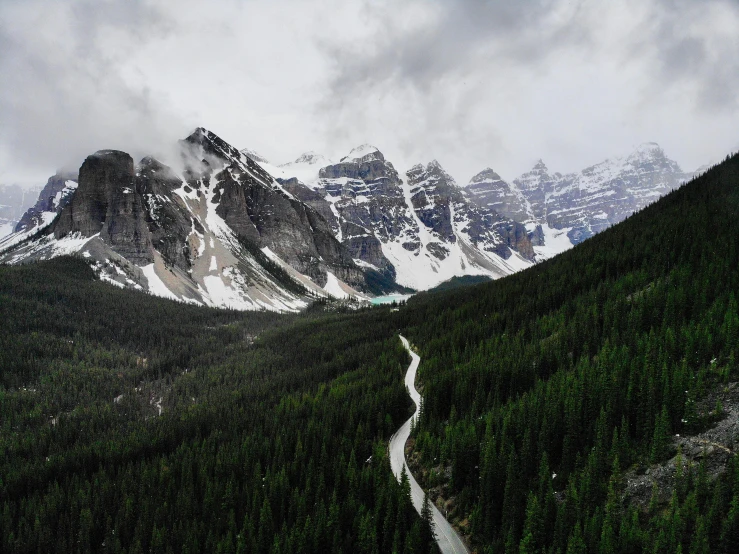 a road winding through a valley with snow capped mountains