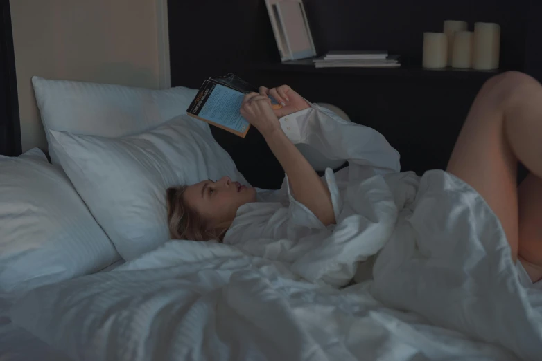 a woman is laying in bed reading a book