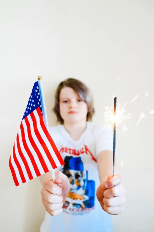 a girl is holding a sparkler and a american flag