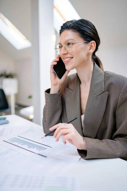 a woman sitting at her desk talking on the phone