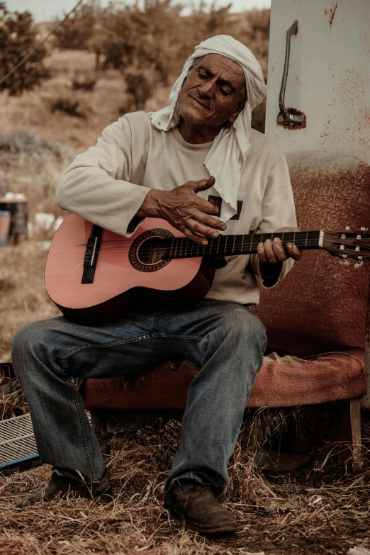 an older man with head covering playing guitar