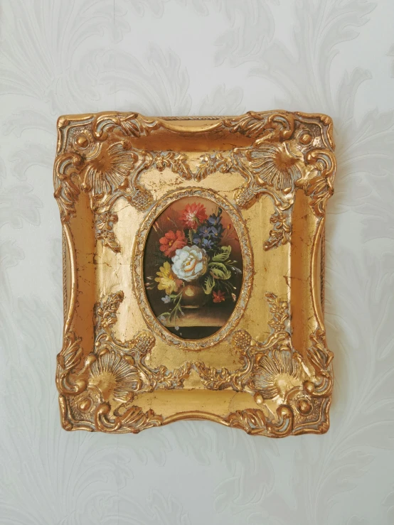 a gold framed painting on wall with white flowers