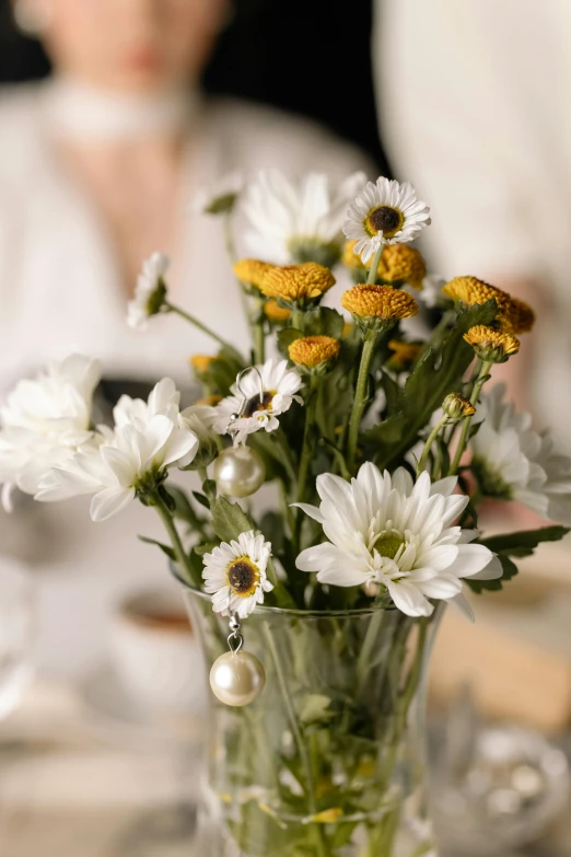 a vase with white flowers is shown with pearls in it