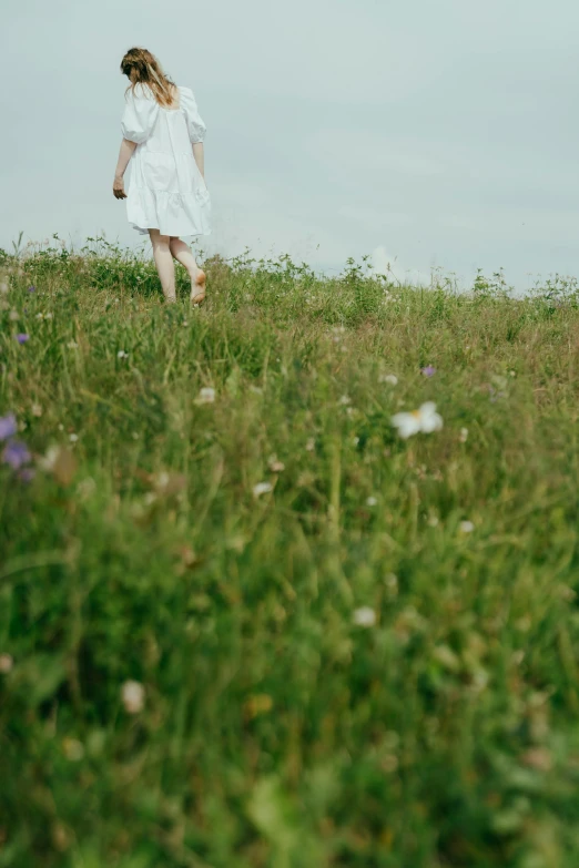 the woman in a dress is walking through a field