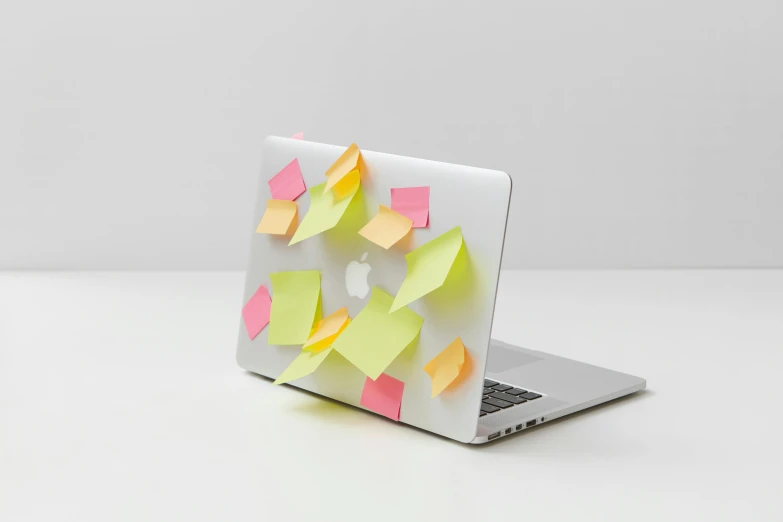 a macbook with yellow and pink sticky notes on it