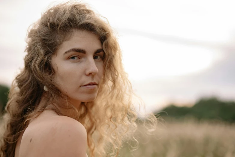 a young woman with long blonde hair is standing in a field