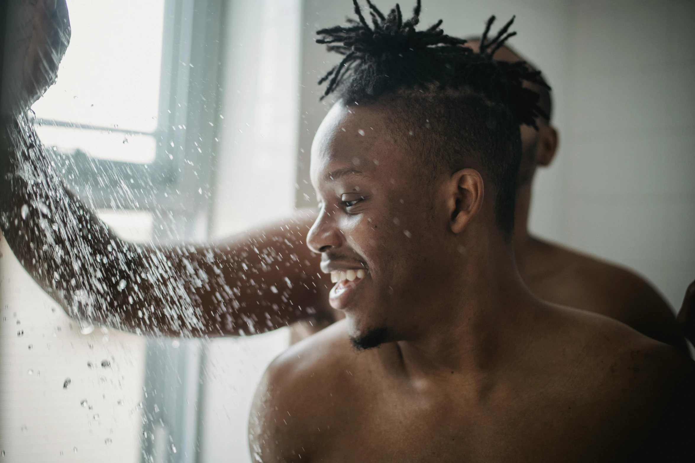 a young man in the shower of water spraying from his hair