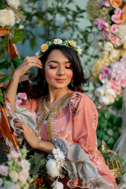 a woman dressed in pink sitting down next to flowers