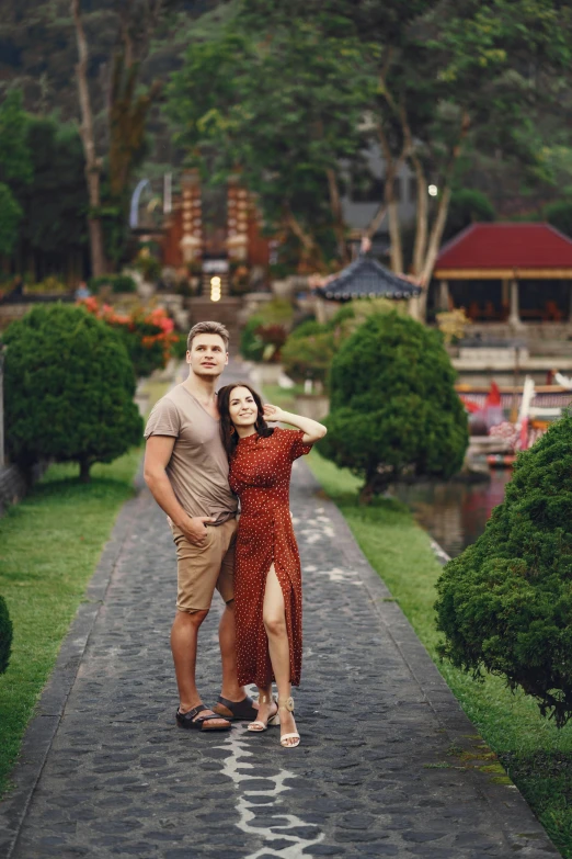 man and woman posing on paved path next to building