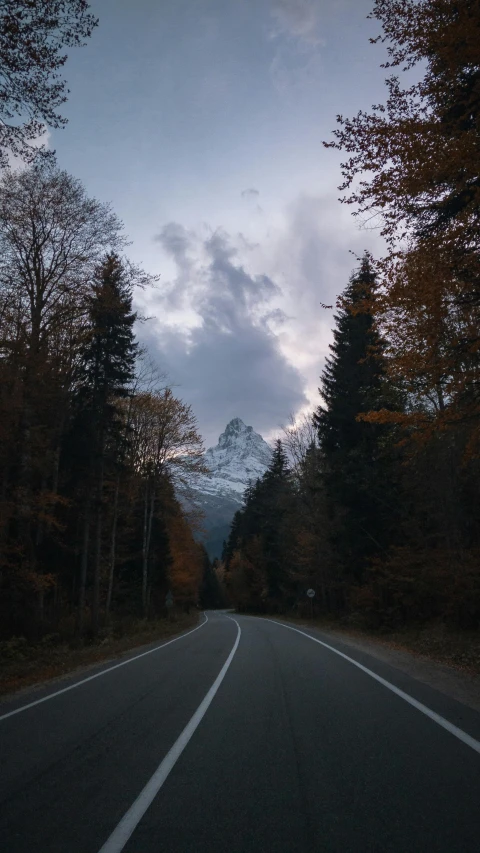 a road is shown at night with a light that looks like soing coming from a snow capped mountain