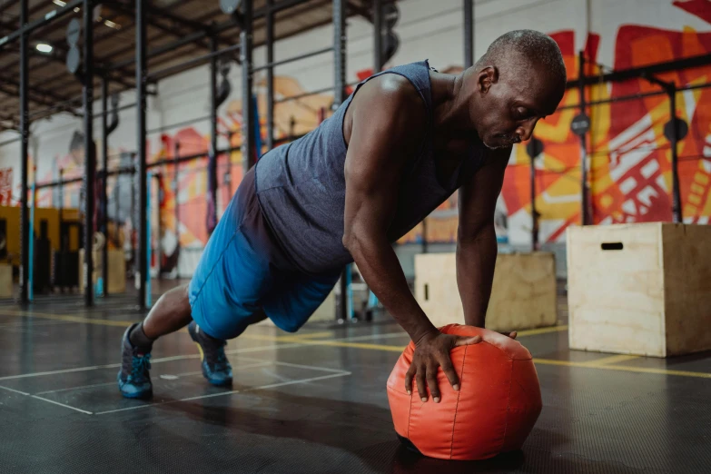 a man on the floor lifting a big orange ball