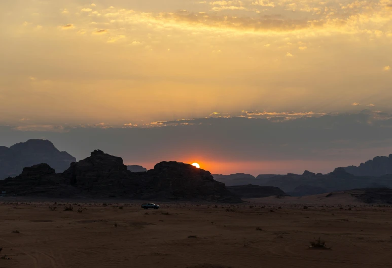 the sun is rising over rocks in the desert