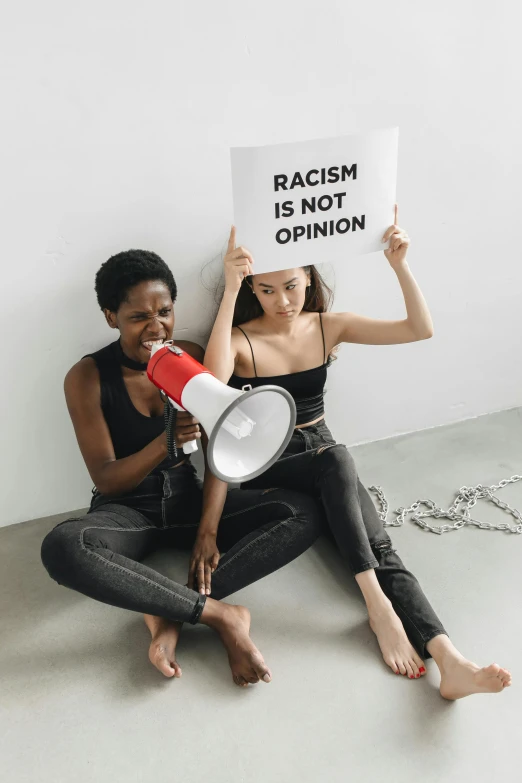 two people sitting on the ground with a sign in front of them