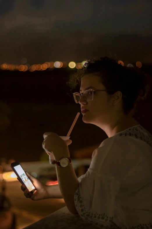 a woman with glasses holding a cellphone and writing on it