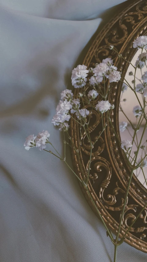 a round mirror that is holding flowers in it