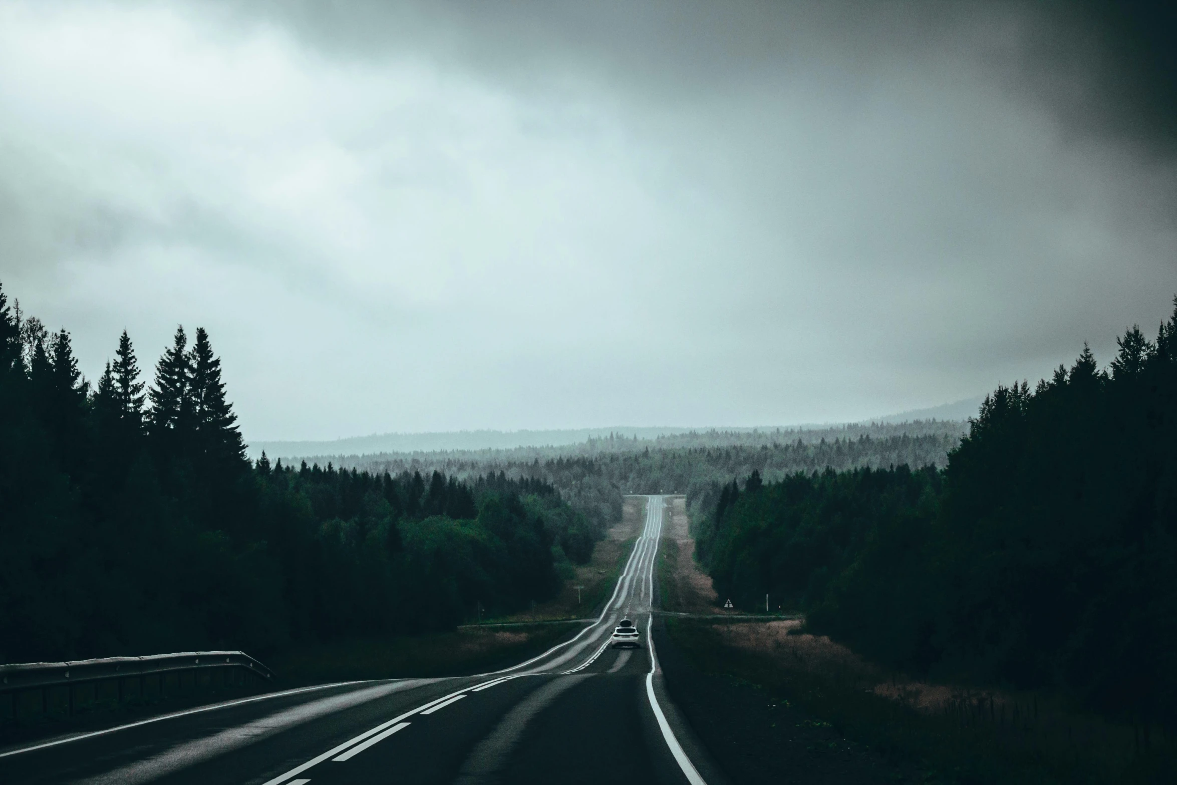 the view of a rural highway through a cloudy sky