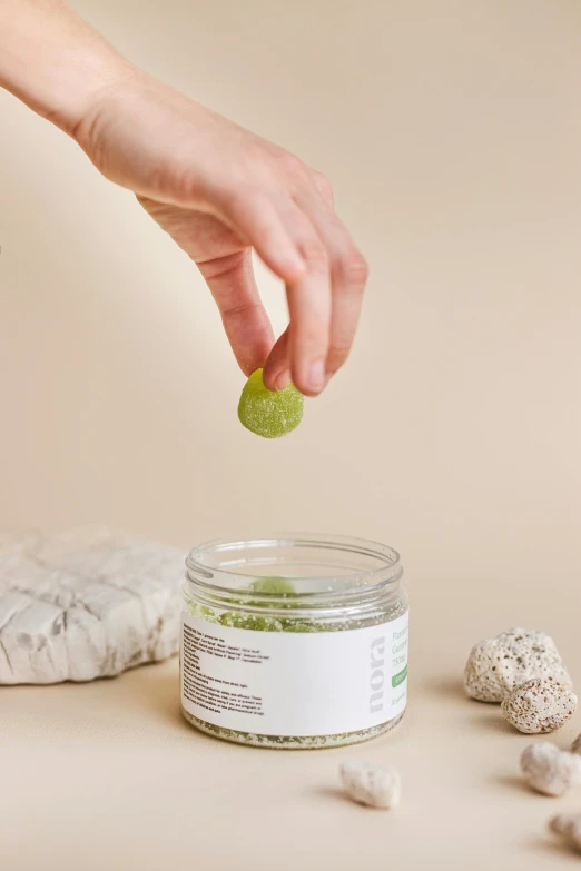 a person's hand dropping lime into a jar with some white eggs on the ground