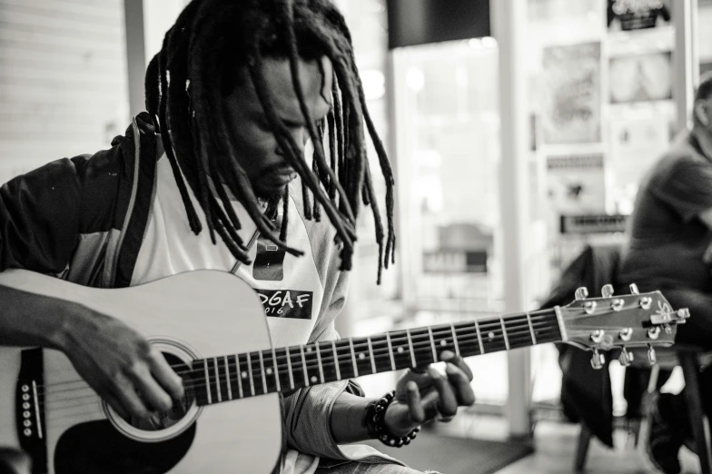 a man playing the guitar with another man playing in background