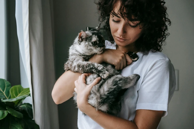 the woman is holding a cat on her shoulder