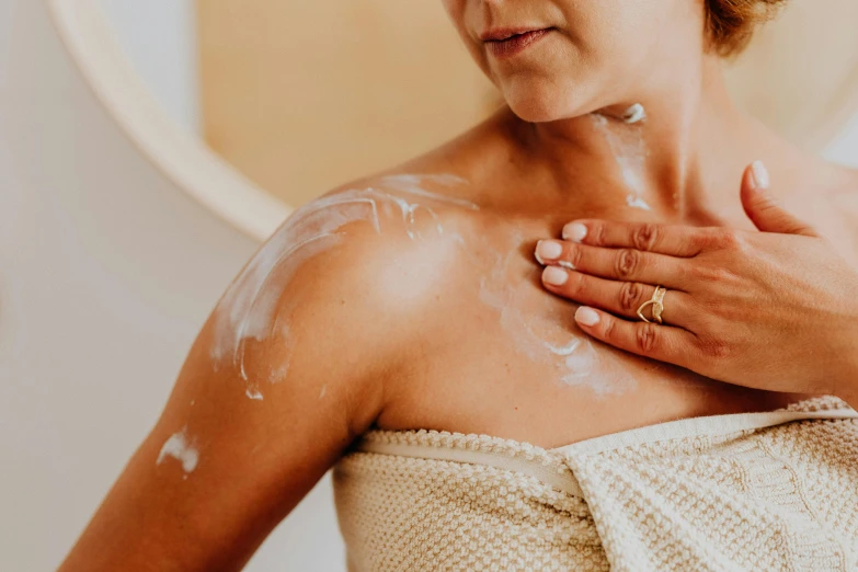 a woman is wearing a towel and rubbing her chest