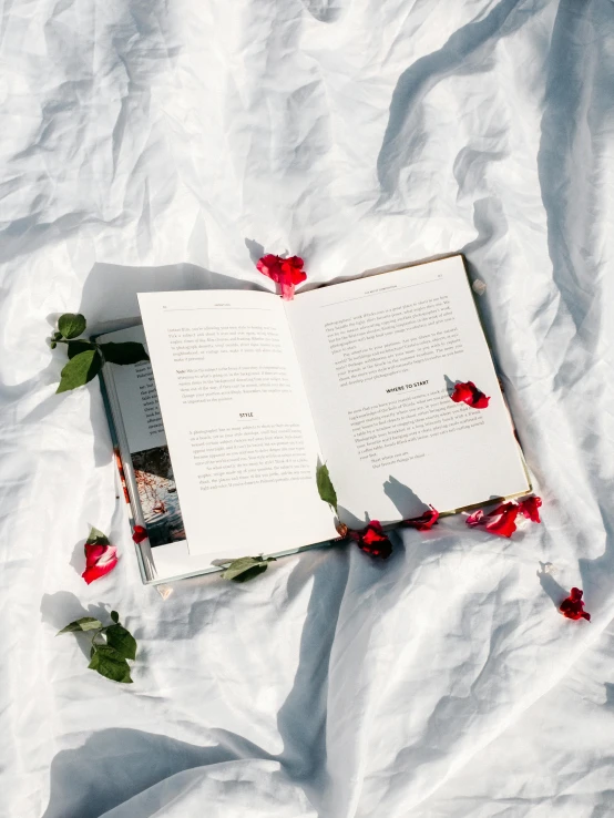 a book open on a bed covered in flowers